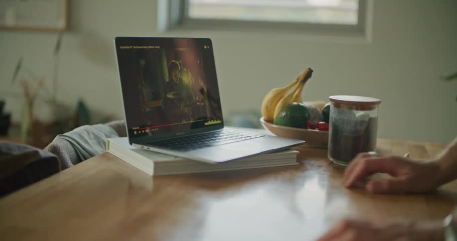 A man stands at a desk looking at a laptop screen
