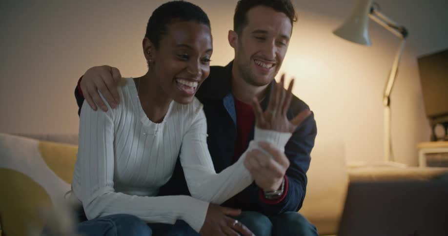 A man and woman proudly show off her engagement ring during a video call