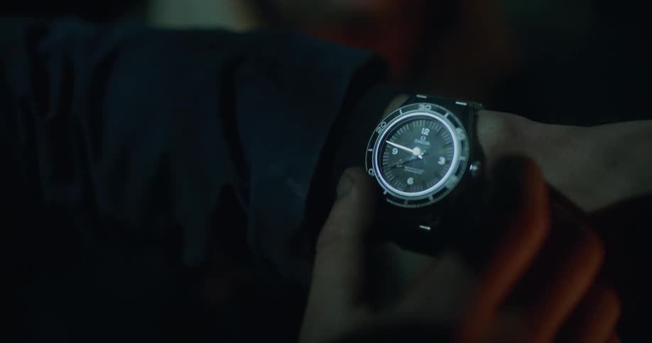 Person in dark area adjusts analog wristwatch