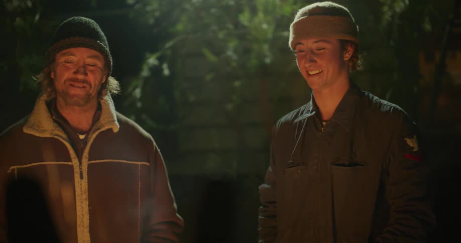 Father and son standing around a campfire talking