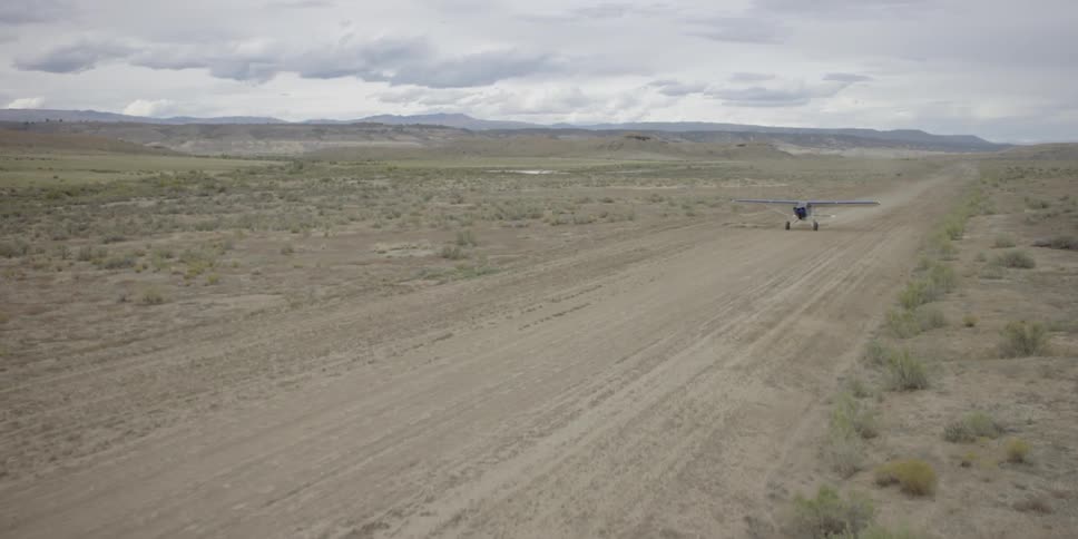 A single-engine plane taxis down a dirt runway