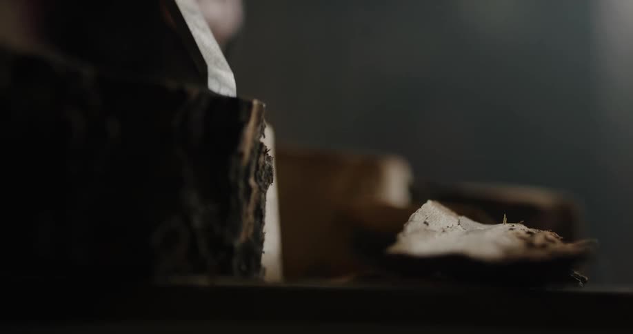 A person in a room chiseling the bark off a log
