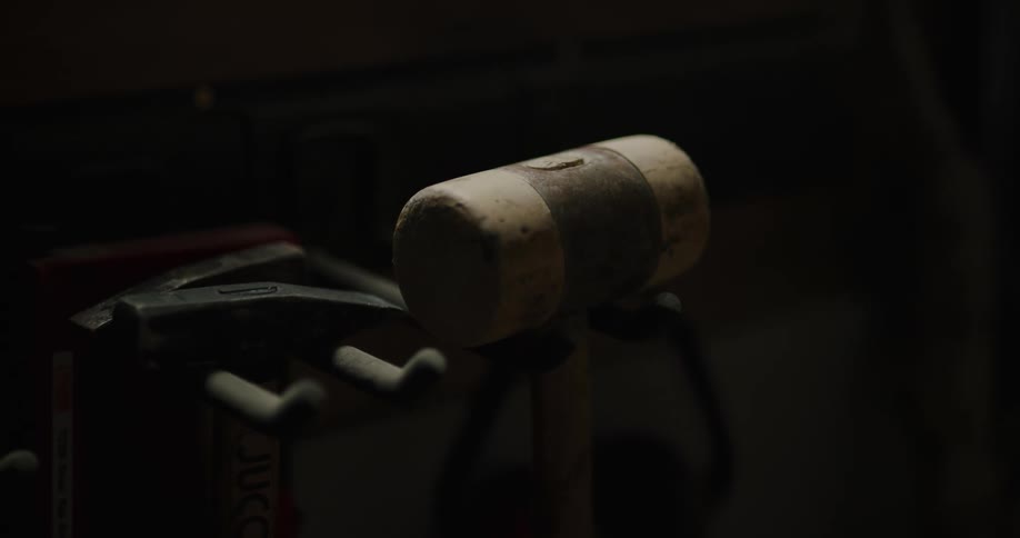 A mallet hanging from a hook in darkness