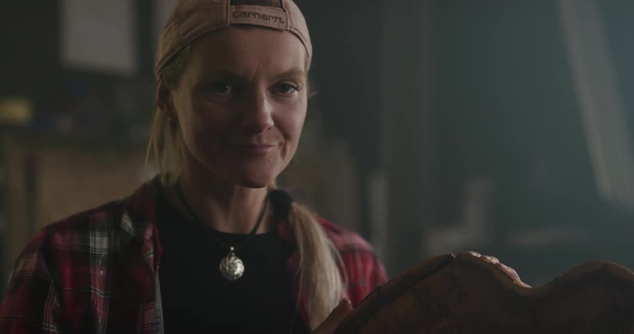 A woman holding a piece of wood in a factory