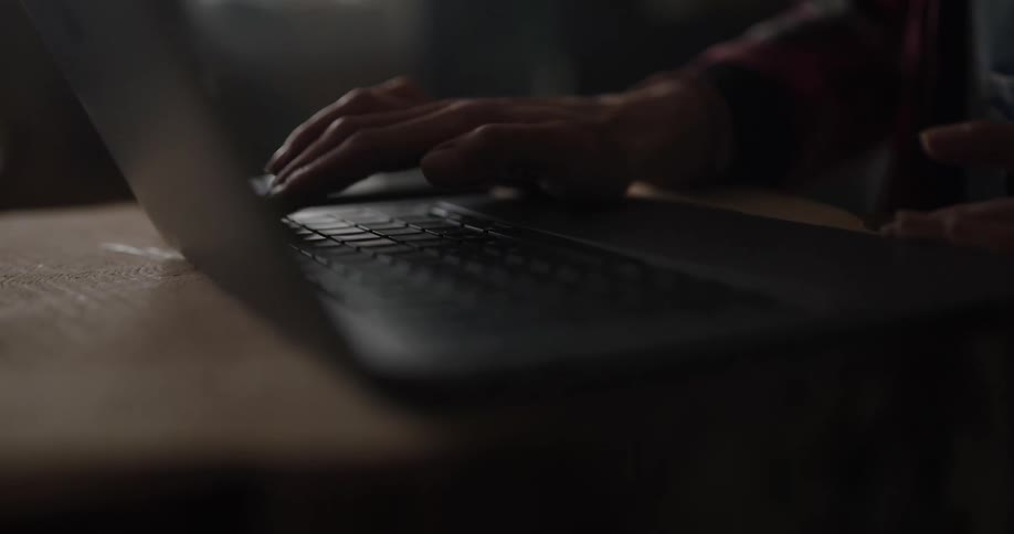 A person is typing on a laptop indoors