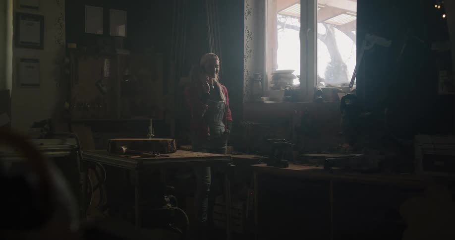 A female standing in a room talking on the phone in a cluttered house