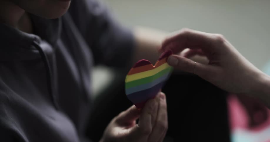 A teenage girl gives another girl a striped heart