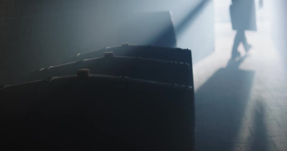 A silhouette of a person walking out of a room with barrels and closing the door