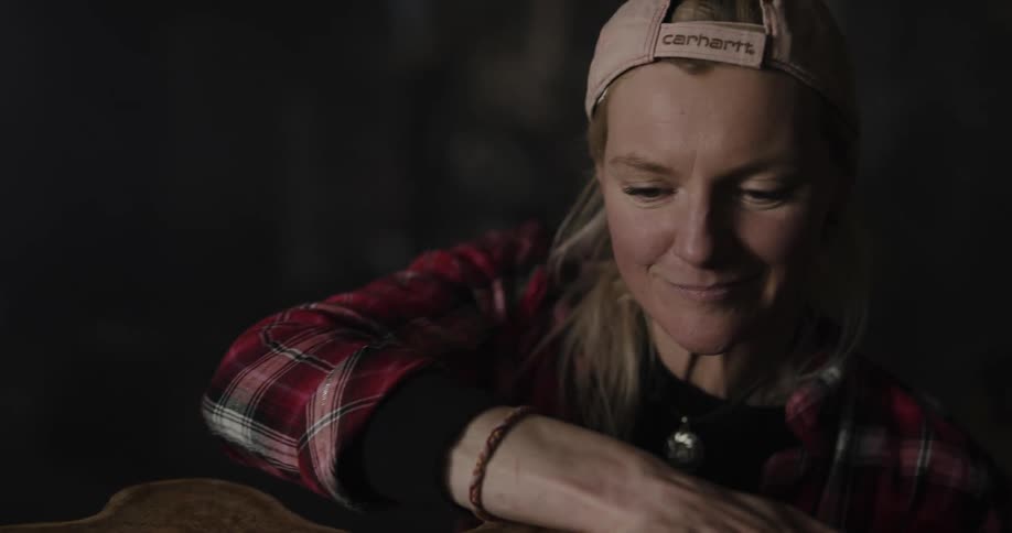 A woman in a room with a hat rubbing a piece of wood with her hand