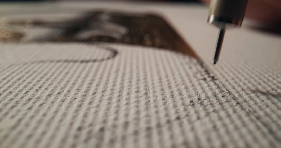 Black ink is dabbed onto fabric made of small dimpled rows