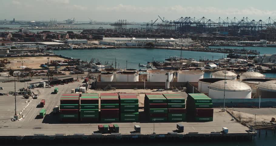A shipping yard with containers and trucks with the sky and clouds in the background