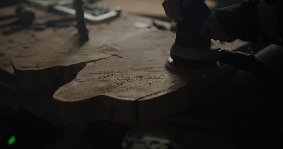 A man sands a cut tree trunk