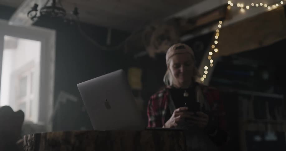 A woman using a scanner and laptop in a dim room with string lights