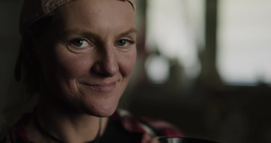 A woman smiles and then takes a drink out of her mug