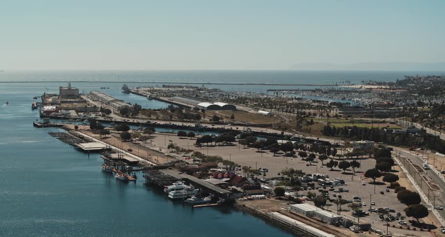Aerial footage of a city with an ocean front next to a parking lot during the day