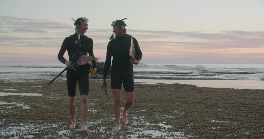 Two men walking on the beach after snorkeling