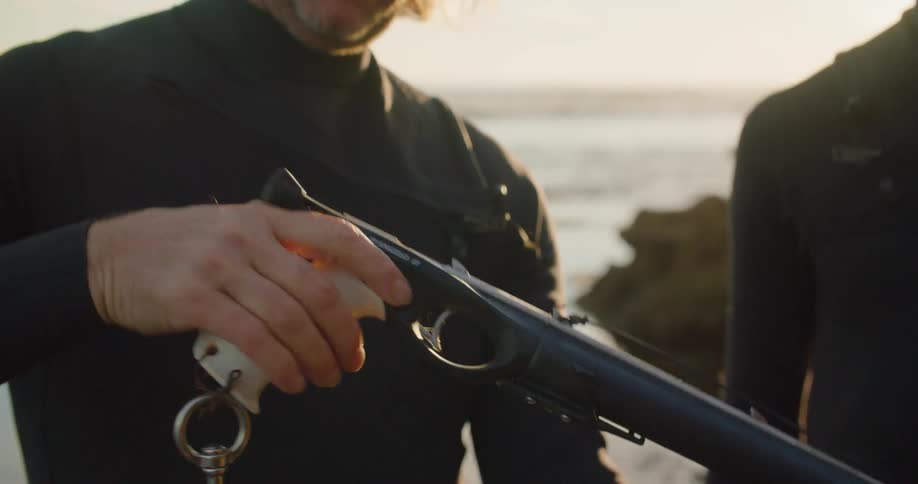Two men examine a harpoon gun