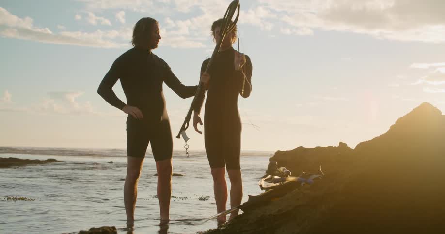 A man shows his son how to use a spear for spearfishing as they stand in the ocean