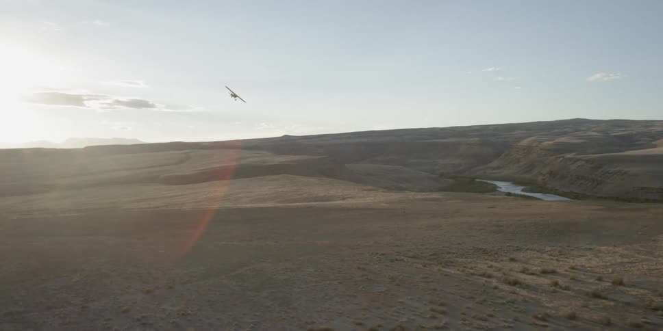 A small airplane makes a turn to fly over river
