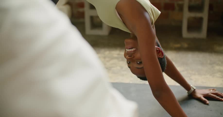 A woman smiles at her partner while holding a downward dog yoga pose