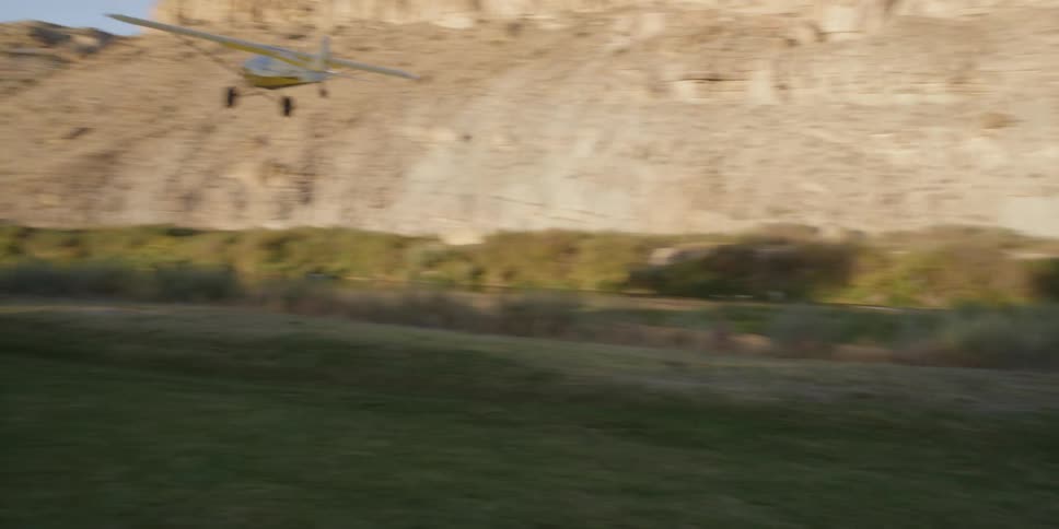 A green field has a plane taking off