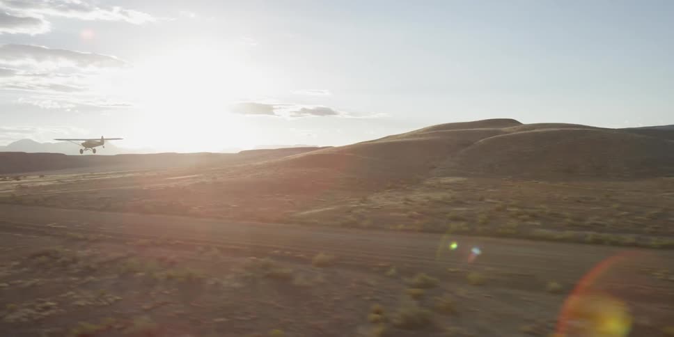 A plane speeds down a dirt runway taking off