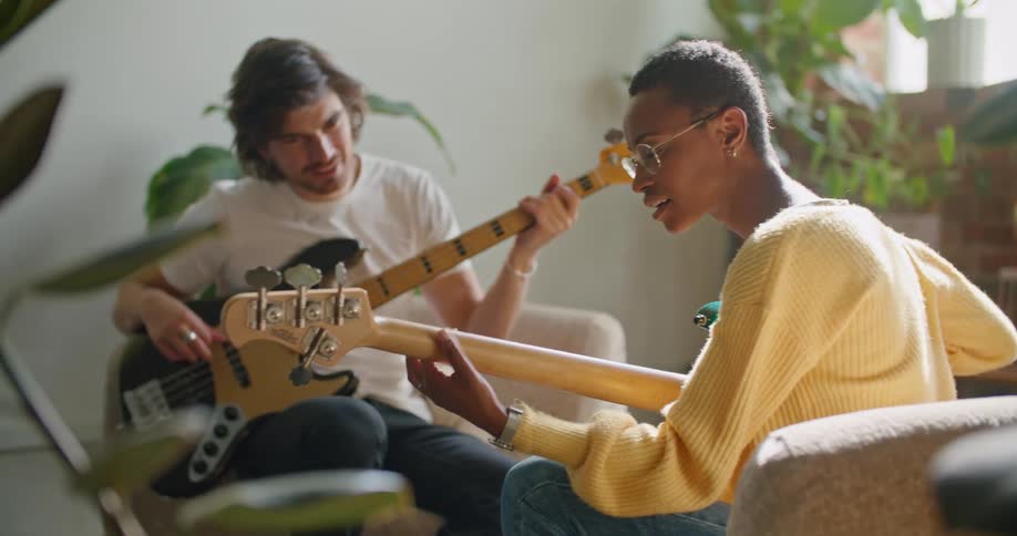 Man and woman are sitting in a room and playing guitar