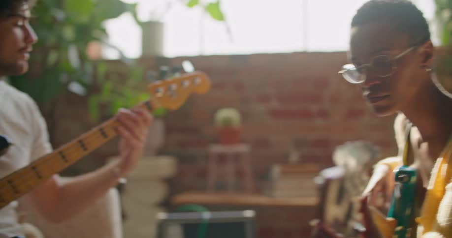 A woman sits while holding a bass guitar and practices playing along with a man