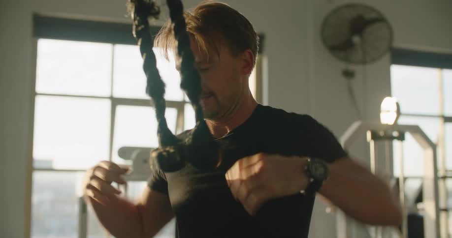 Man straining pulling on gym equipment