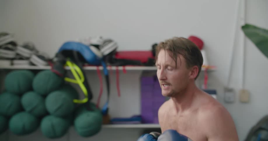 A man is boxing indoors during the day