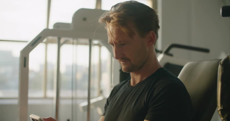 A man texting and smiling while in the gym