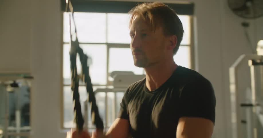 A man exercises using a pulldown machine in a gym during the day