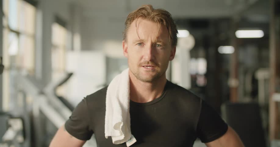 A man is standing in a gym during the day