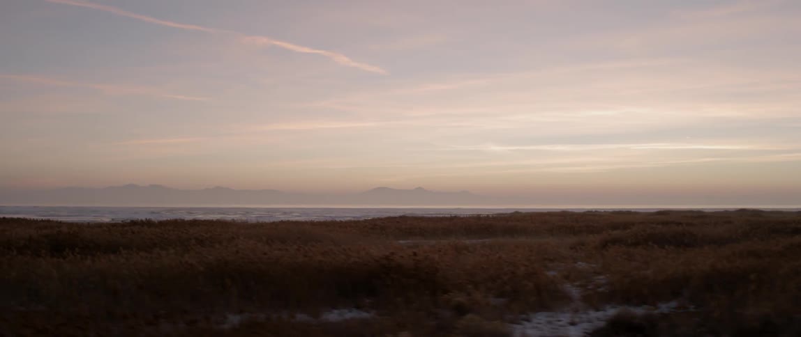 A field has the sun setting in the distance
