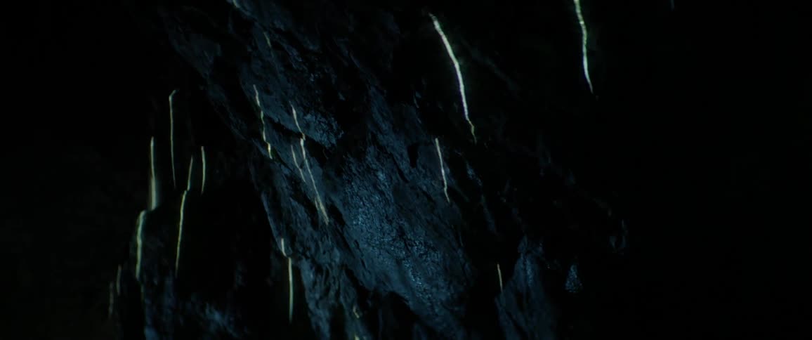 The light shoots up the side of the rocks in the dark