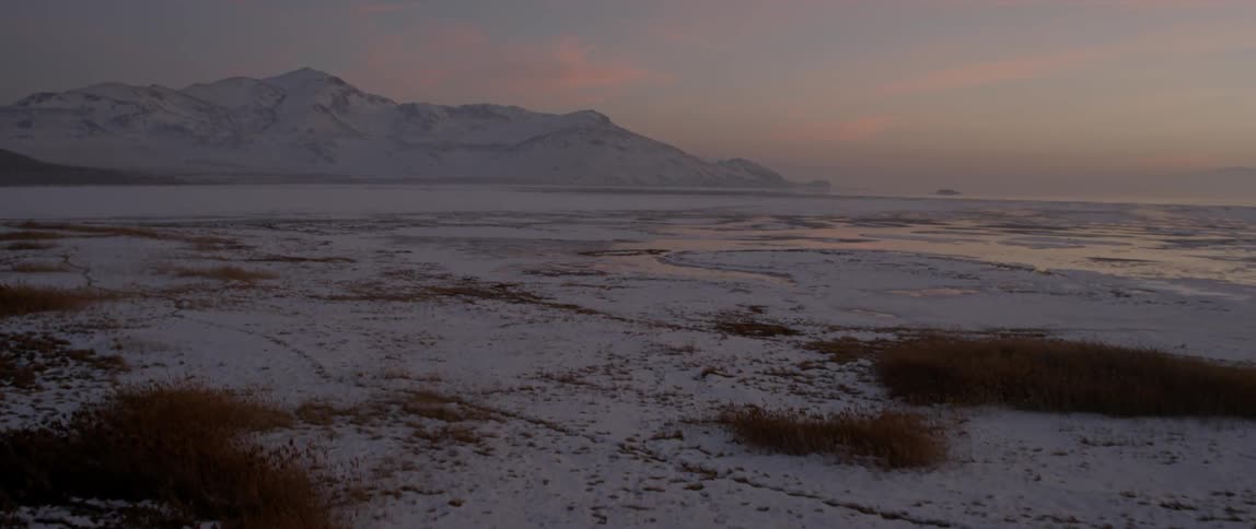 Moving over a snow covered field at sunset