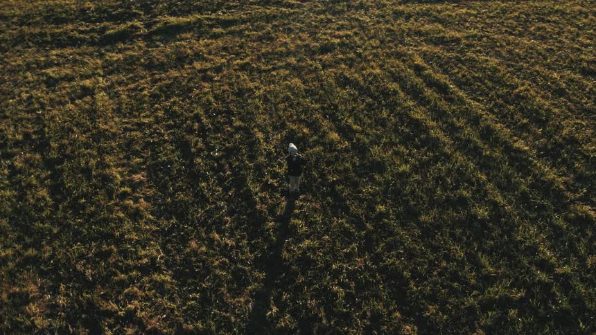 Boy standing on a field in the morning flying a drone using a remote control