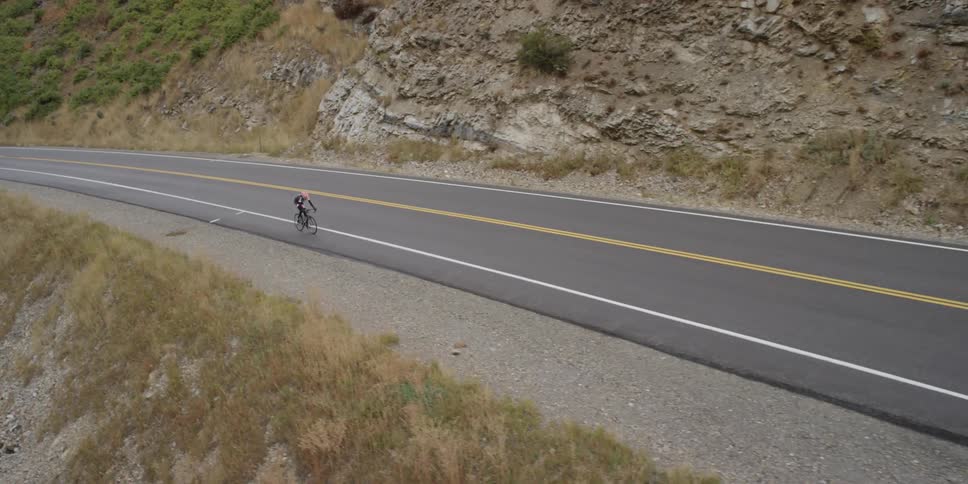 A cyclist on a mountain side road during the day