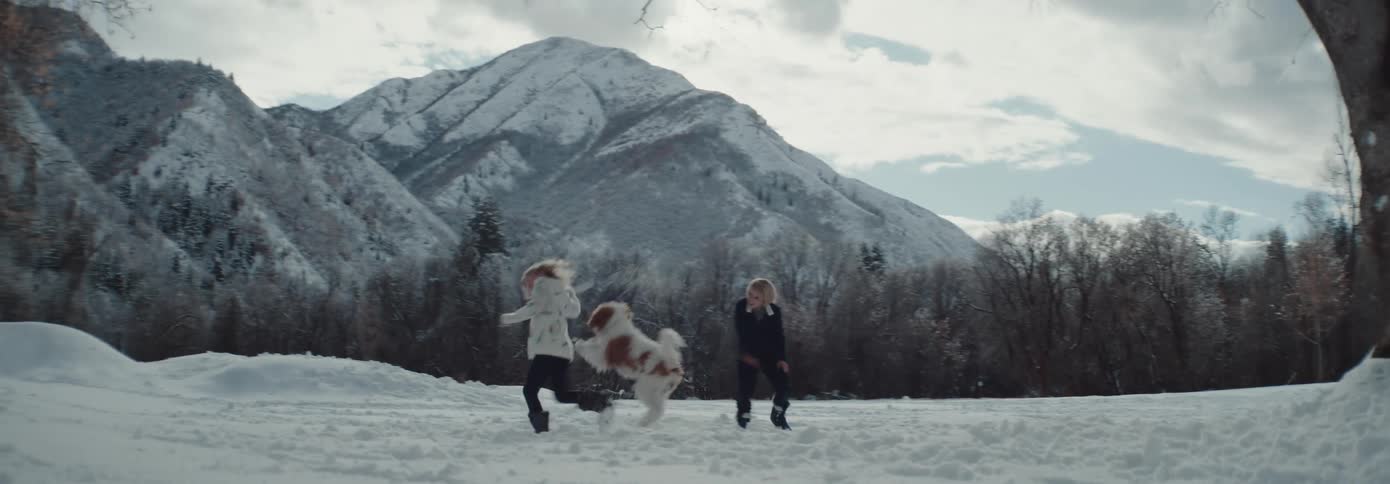 Young siblings and their pet dog playing on the snow in the countryside near the mountains