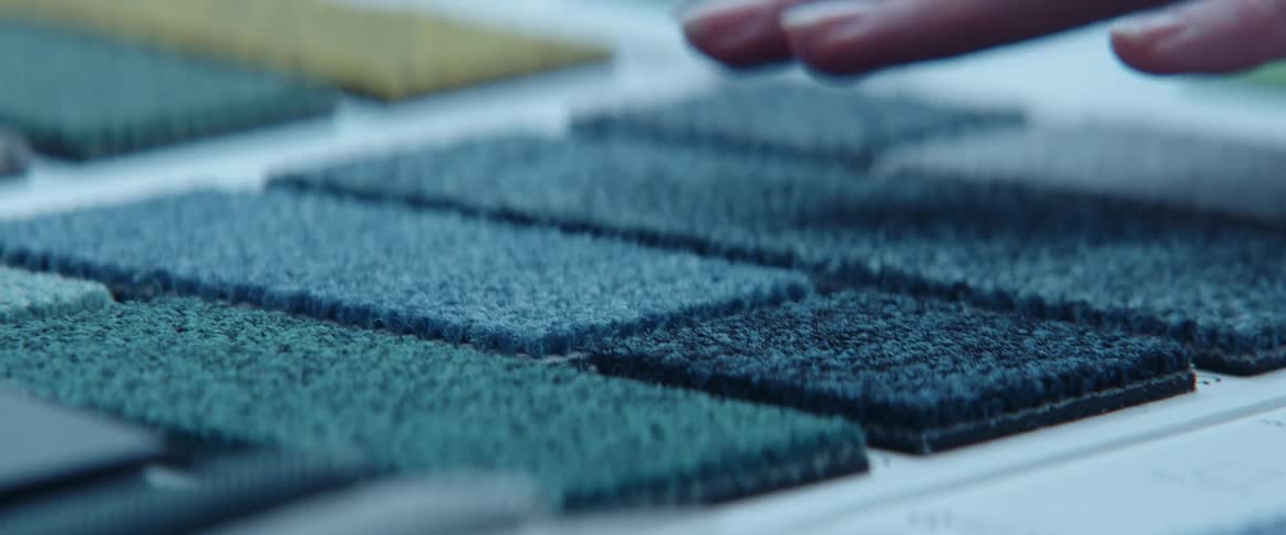 A person touching different fabrics on a table