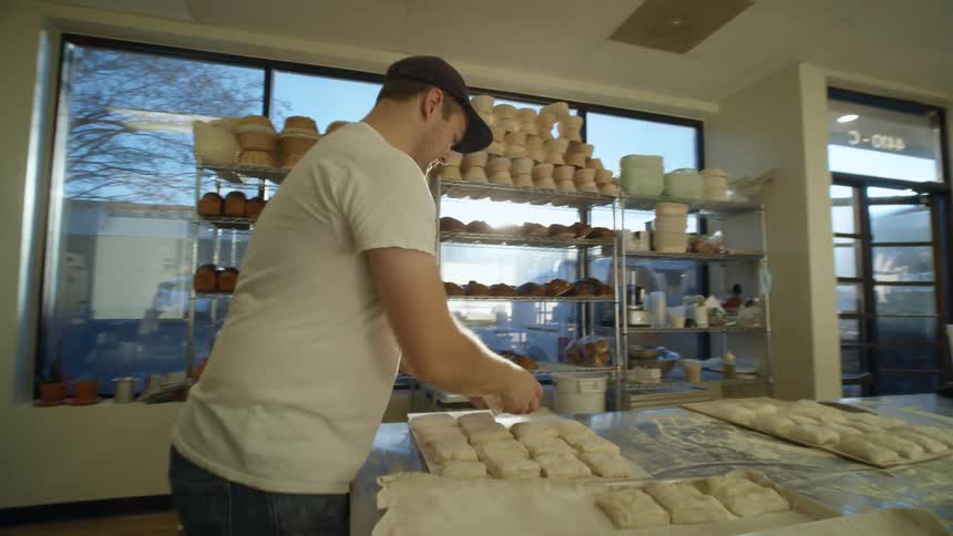 A man works with pieces of dough in a bakery kitchen