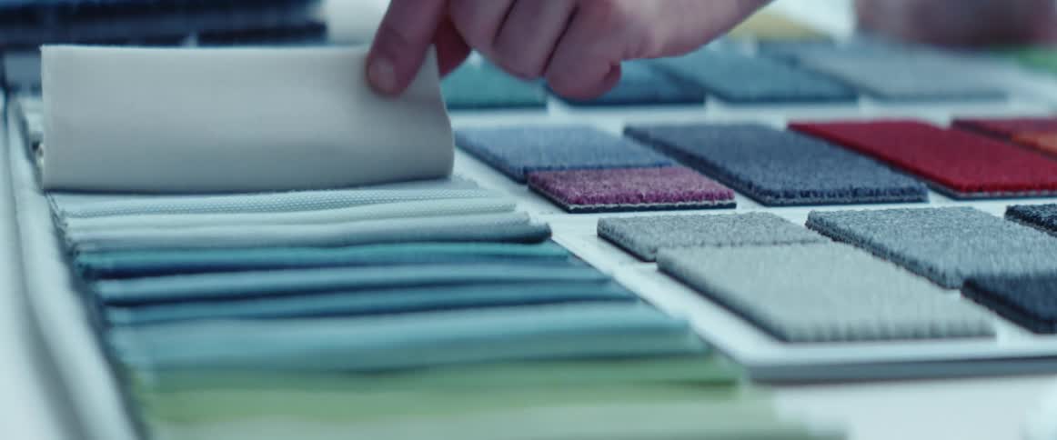Man testing the quality of samples of fabric over a desk