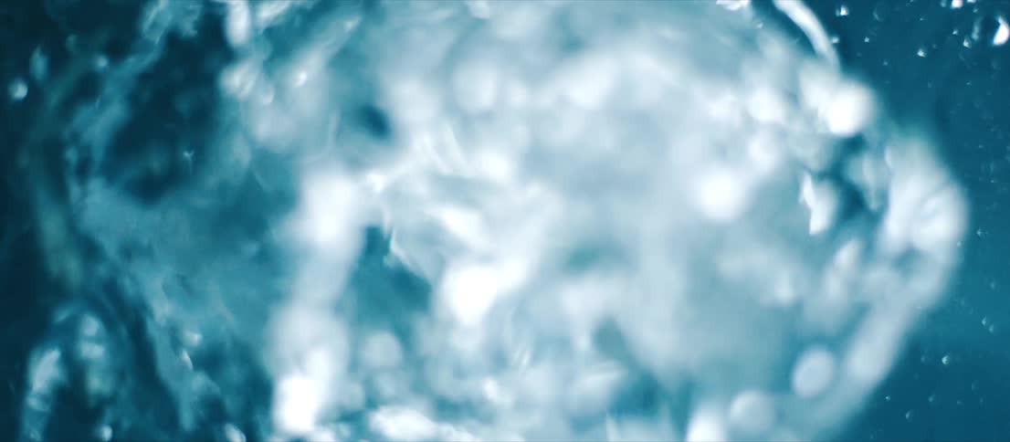 Bubbles form and bursts in clear translucent shimmering liquid