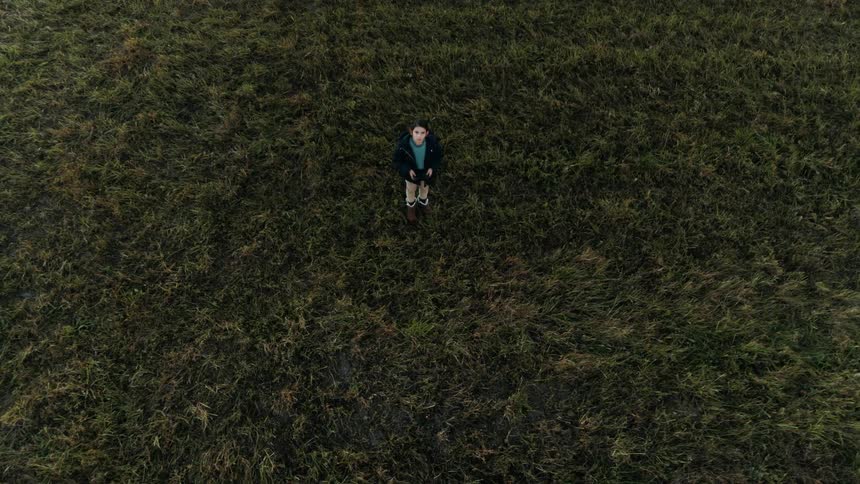 A child is standing in an open field looking up