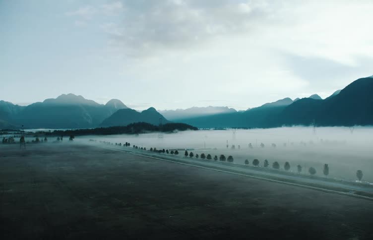 Fog covers area between mountains and road bordering beach