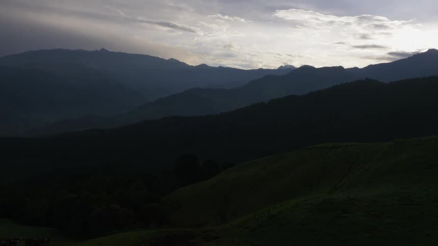 A landscape with hills and trees a mountain range the sky and clouds in the background