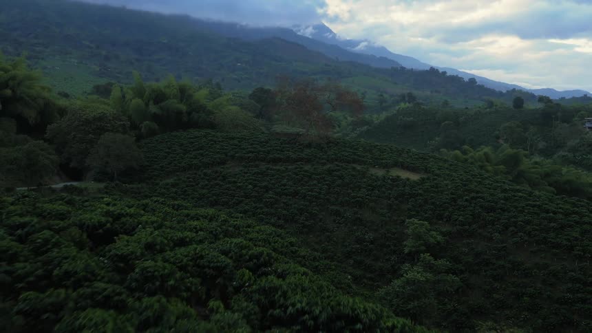 An aerial view of a hilly landscape with mountains in the distance