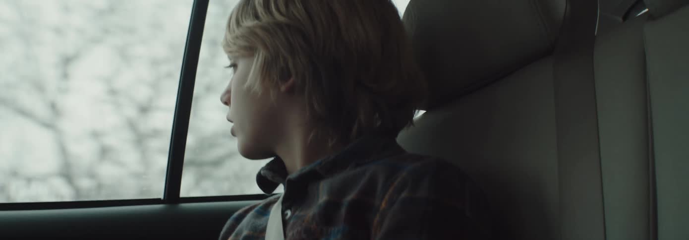 A child sits in a vehicle looking out of the window at the mountains