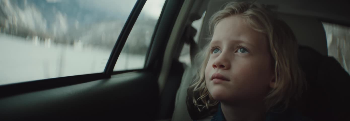 A young child smirking while riding in a moving vehicle
