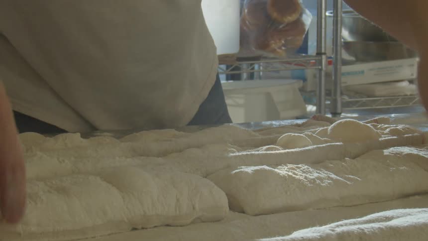 A baker preparing bread dough on a countertop